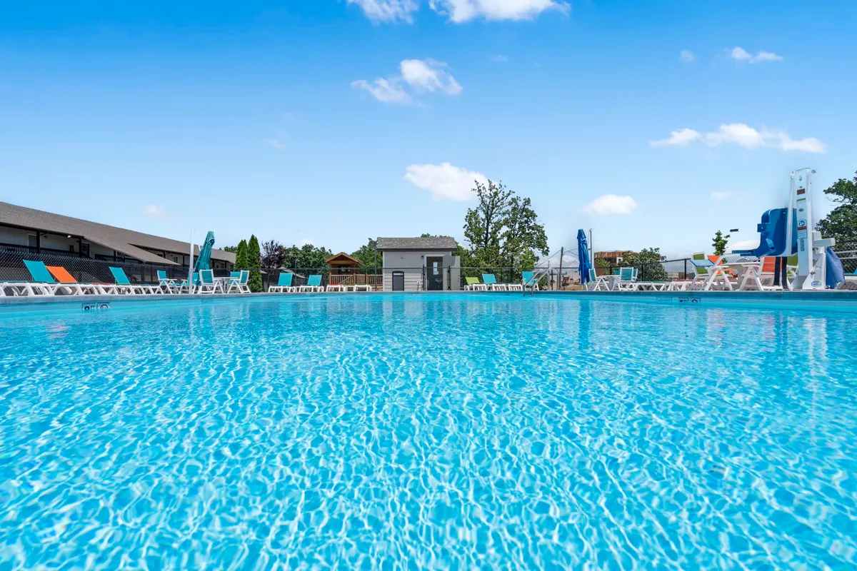 This cheerful exterior image features a sparkling outdoor pool, lounge chairs, a slide, and a sunny atmosphere—inviting guests to enjoy socializing and playing under the sun during the warmer months.