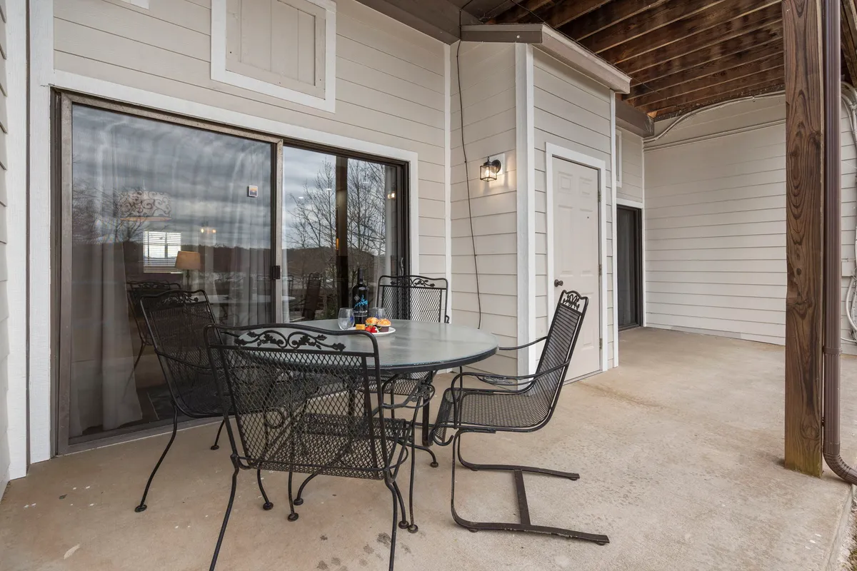 A charming patio set with a metal table and chairs just outside a glass sliding door, enhanced by a decorative light fixture. The space is ideal for enjoying morning coffee or evening gatherings, seamlessly extending the living space outdoors.
